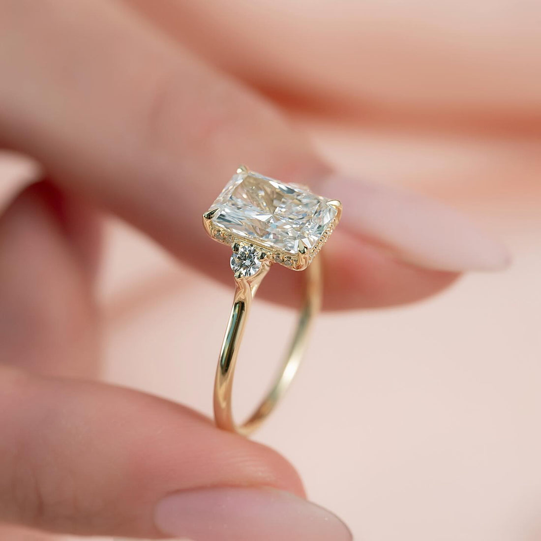Radiant cut moissanite round side three stone ring side profile in yellow gold