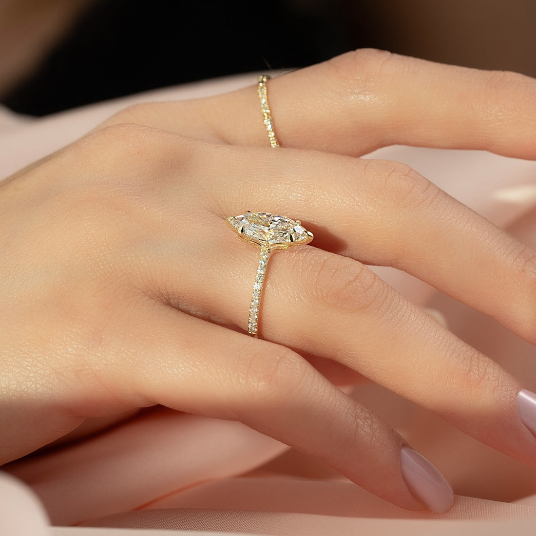 Marquise moissanite pave band solitaire ring worn on hand in yellow gold