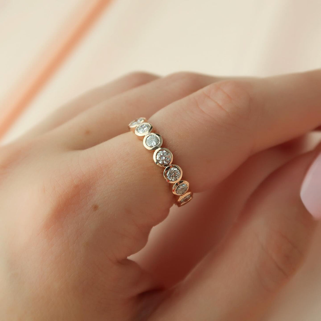 Round moissanite bezel set full eternity band in rose gold