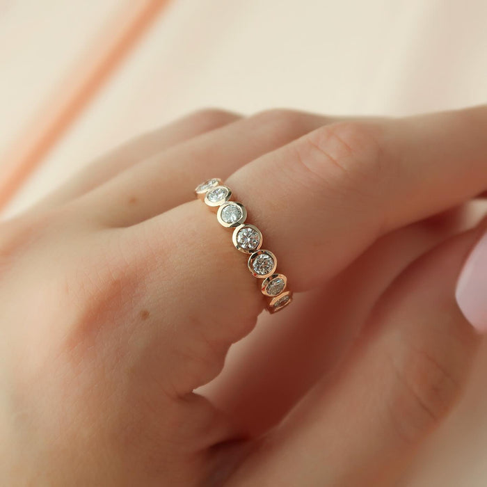 Round moissanite bezel set full eternity band in rose gold