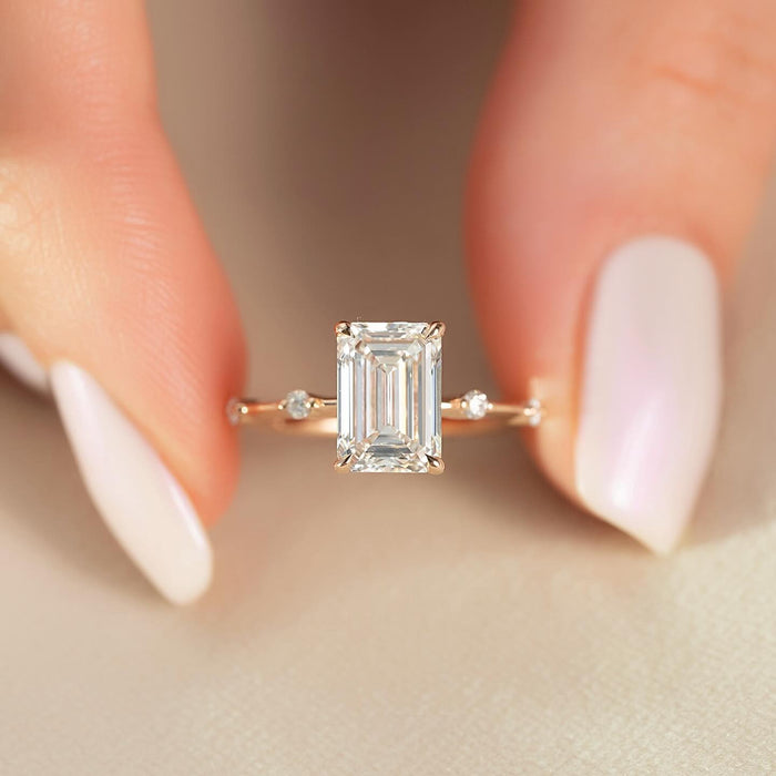 Emerald cut moissanite ring with spaced round accents on slim rose gold band