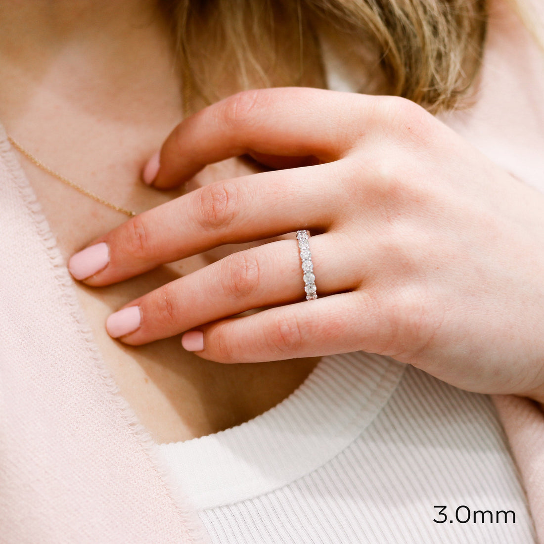 White gold round moissanite eternity band worn on a hand with a 3.0 mm label