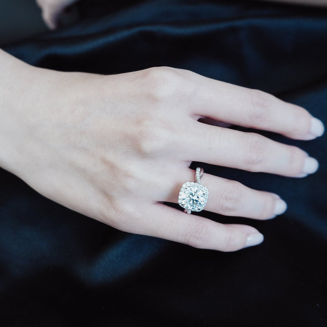 Round cut lab grown diamond halo ring with a twisted pave band worn on the hand