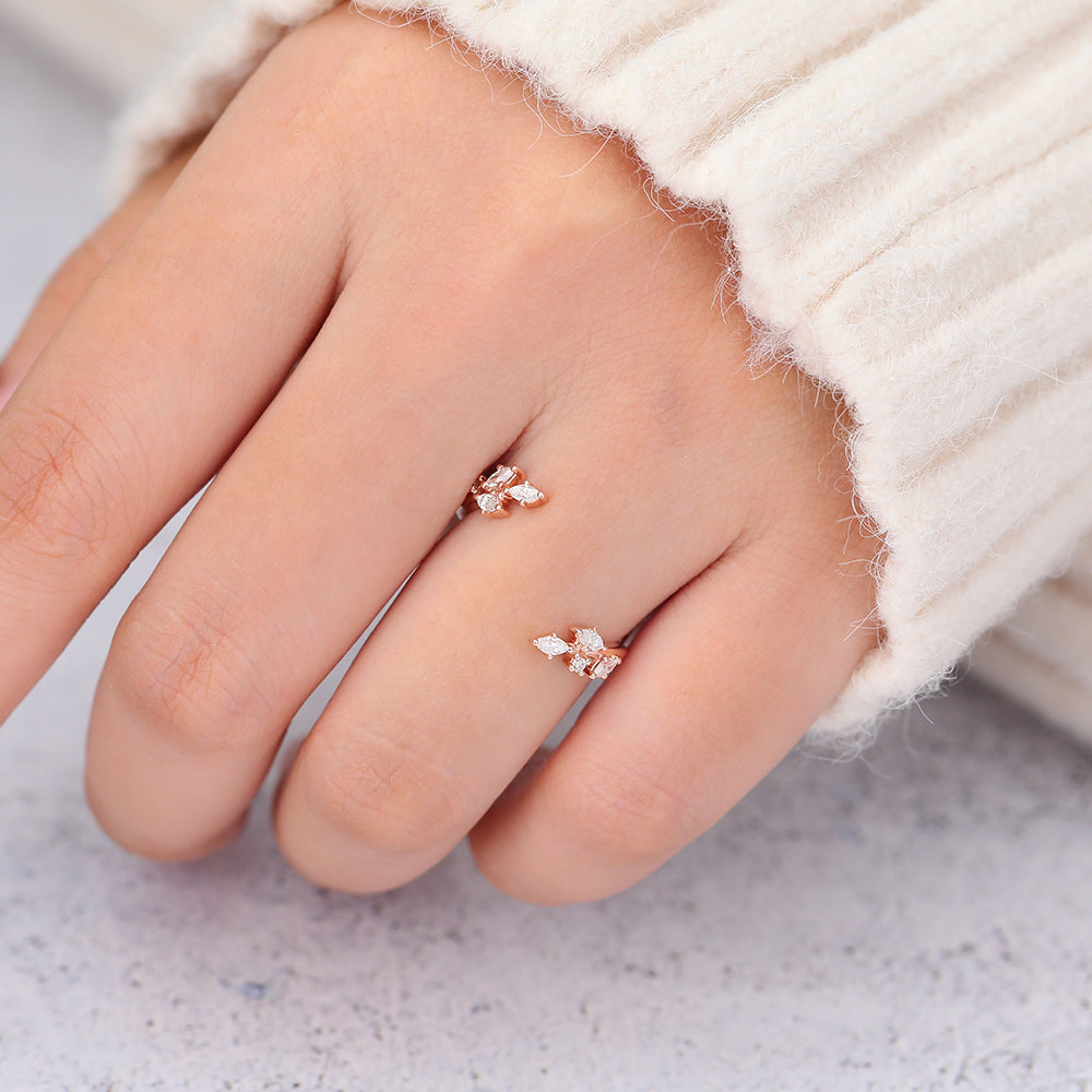 Rose gold open leaf moissanite band worn on a finger next to a cream sweater