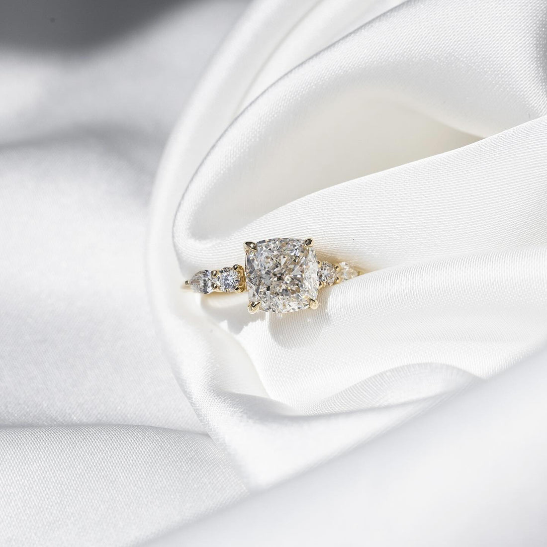 Cushion cut moissanite ring with pear and round cluster side accents in 14K yellow gold