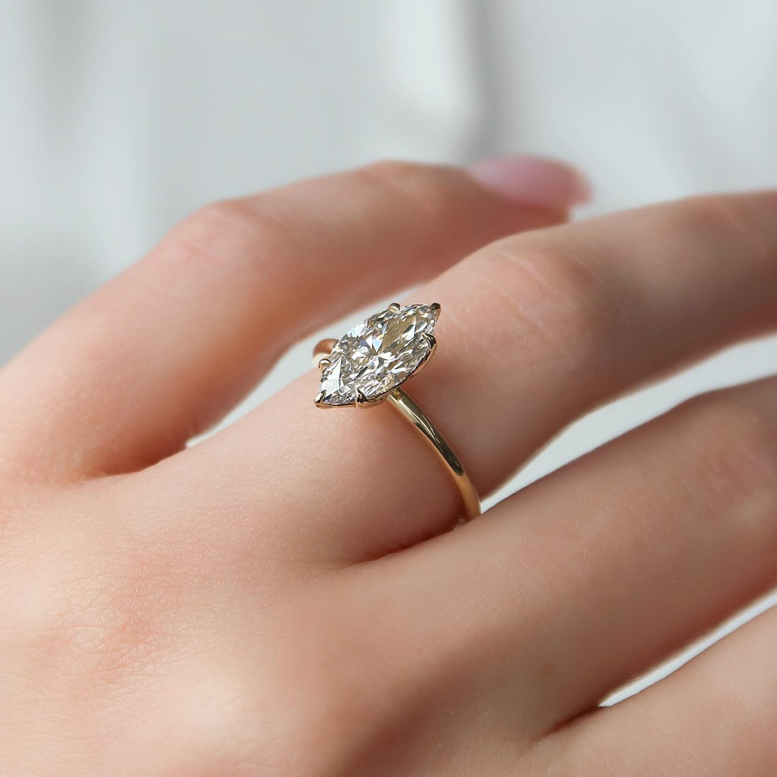 Marquise moissanite solitaire ring with thin band in 14K yellow gold on hand
