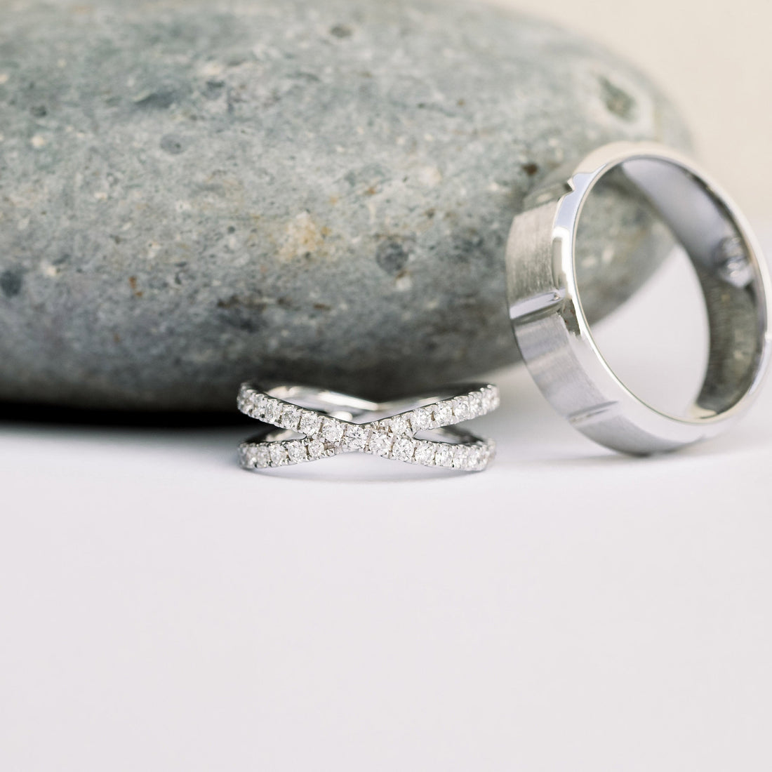 White metal crossover pave wedding band with round moissanite beside a wide plain band, the plain band is not included
