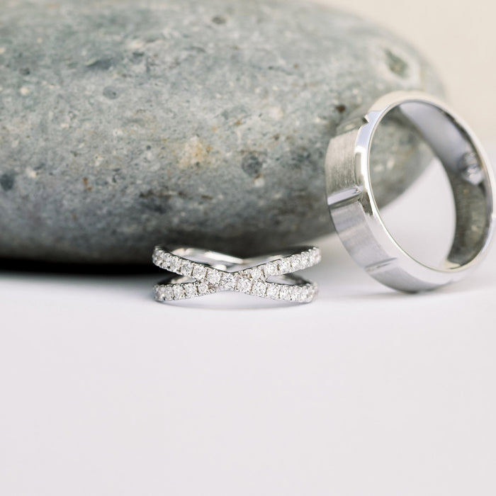 White metal crossover pave wedding band with round moissanite beside a wide plain band, the plain band is not included