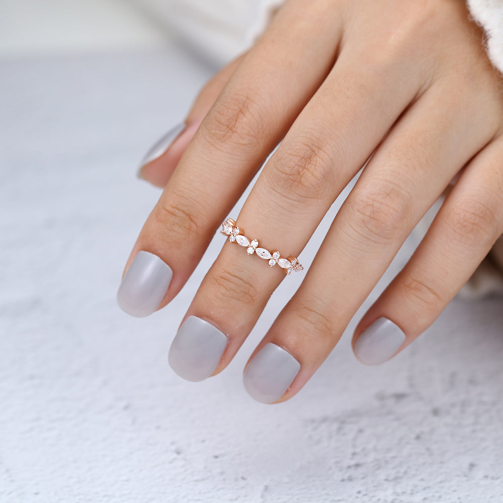 Rose gold marquise and round moissanite cluster band worn on a finger