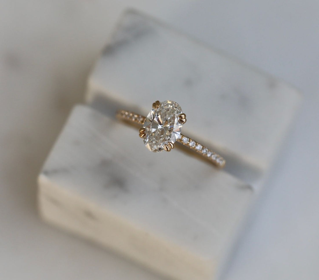 Oval cut lab grown diamond solitaire ring on a pave band in yellow gold