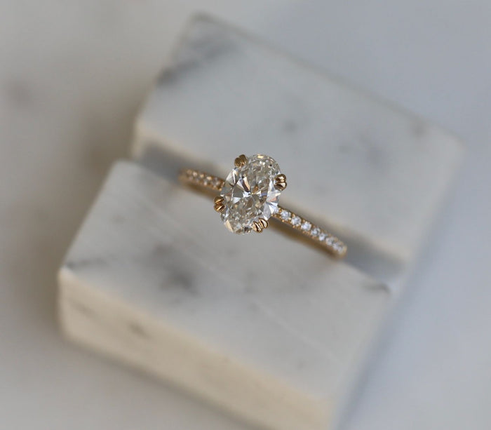 Oval cut lab grown diamond solitaire ring on a pave band in yellow gold