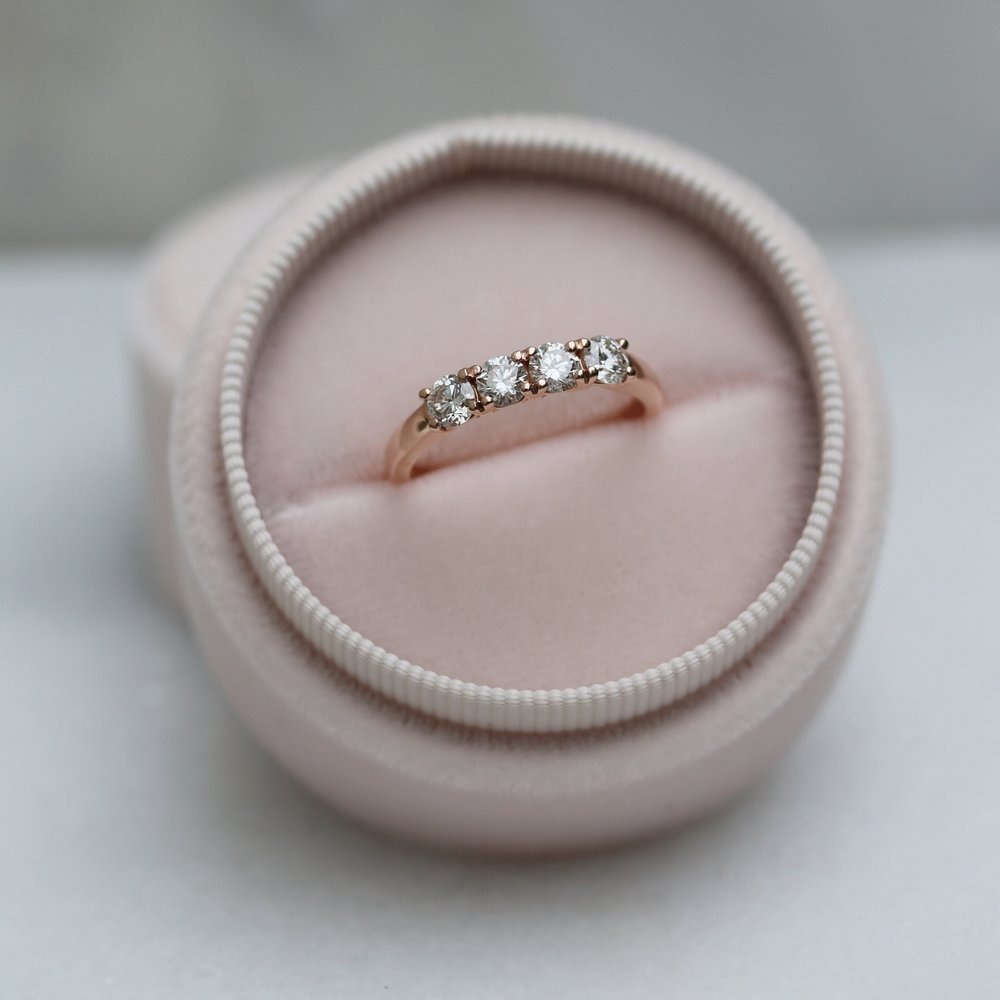 Round moissanite four stone stacking wedding band in rose gold in a pink ring box