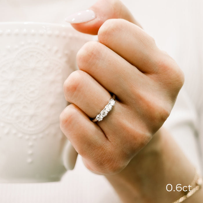 Four stone round moissanite stacking band worn on a finger