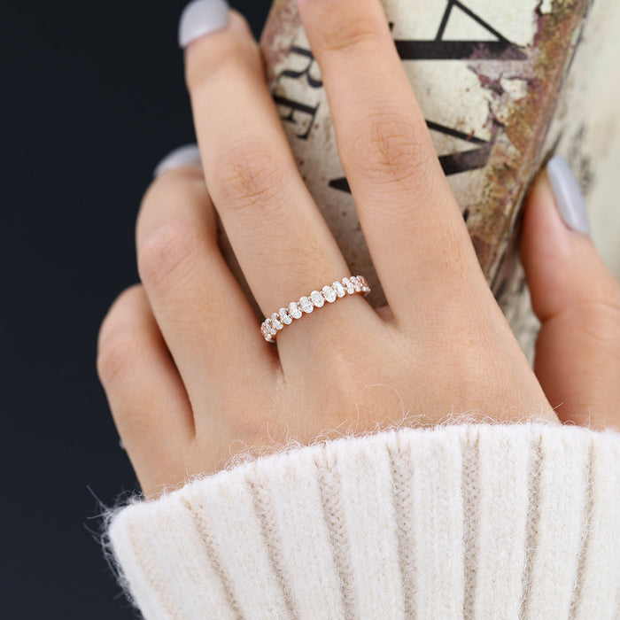 Oval moissanite full eternity wedding band in rose gold worn on the finger
