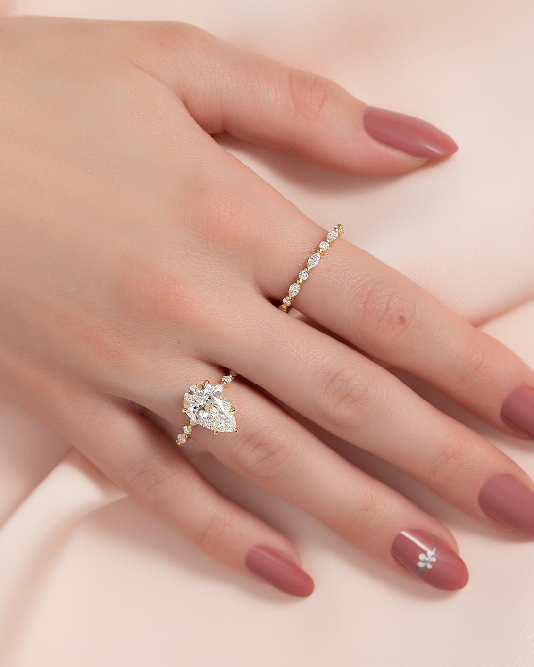 Pear cut moissanite hidden halo marquise accent ring in 14K yellow gold on hand