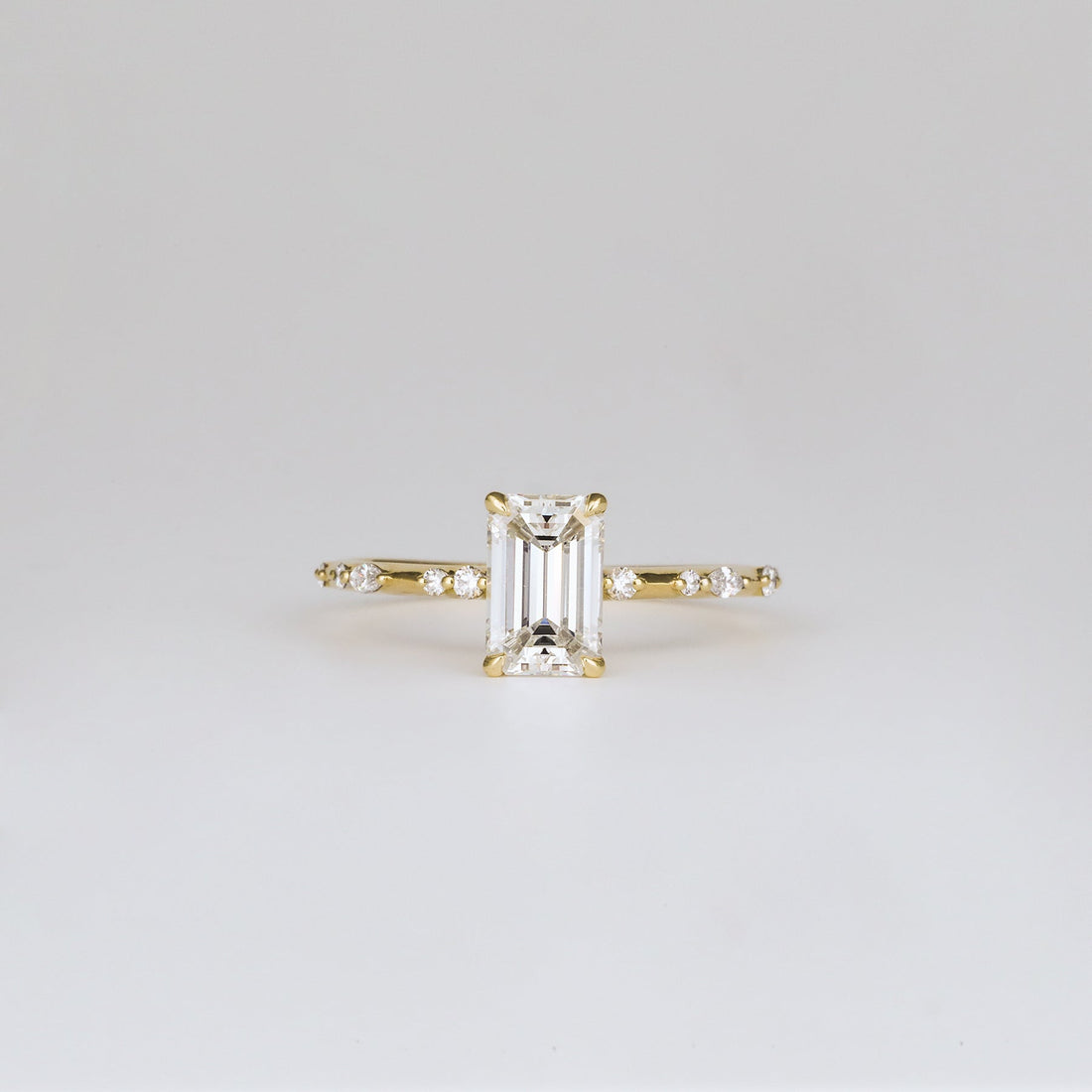 Emerald cut lab grown diamond ring on a slim flush set band in yellow gold