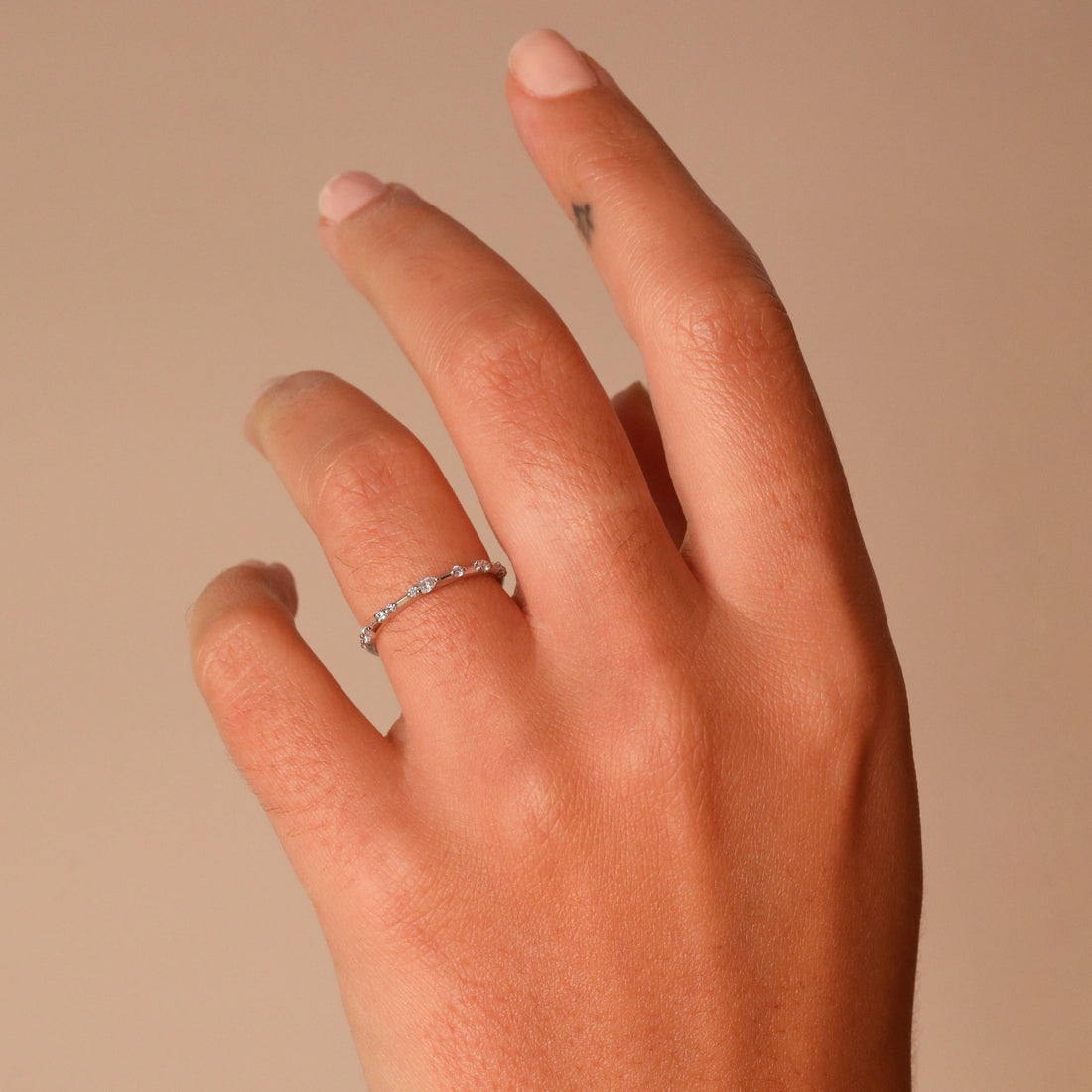 Dainty round and pear lab grown diamond wedding band in white metal worn on a hand