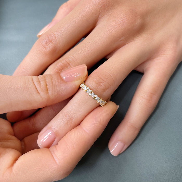 Round and marquise moissanite cluster wedding band in yellow gold worn on a finger