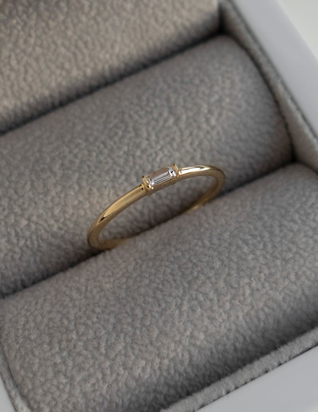 Slim gold stacking ring with one baguette cut moissanite in a ring box
