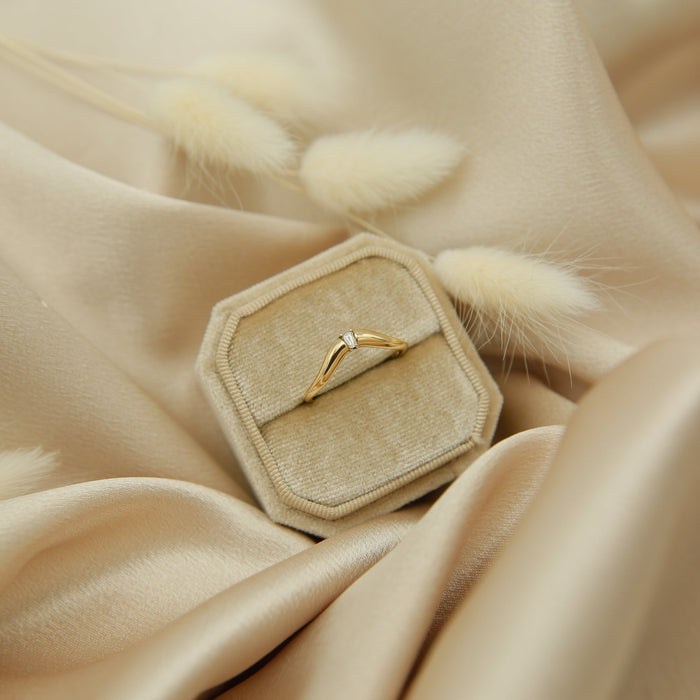 Curved wedding band with a tapered baguette moissanite in a ring box