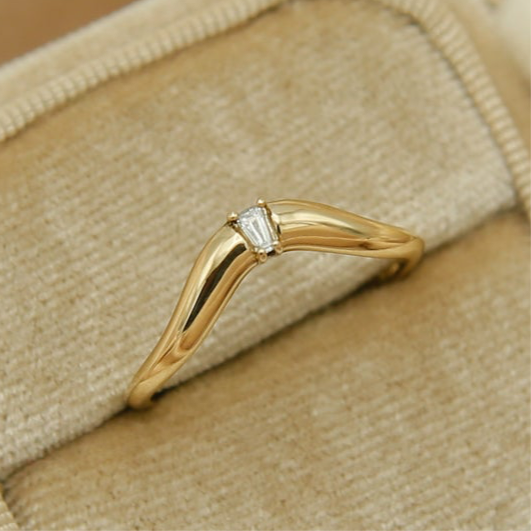 Close view of a tapered baguette moissanite curved band in yellow gold
