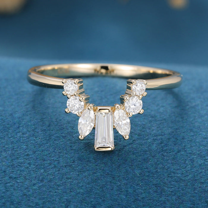 Front view of a curved moissanite wedding band with a center baguette, two marquise and four round stones in yellow gold