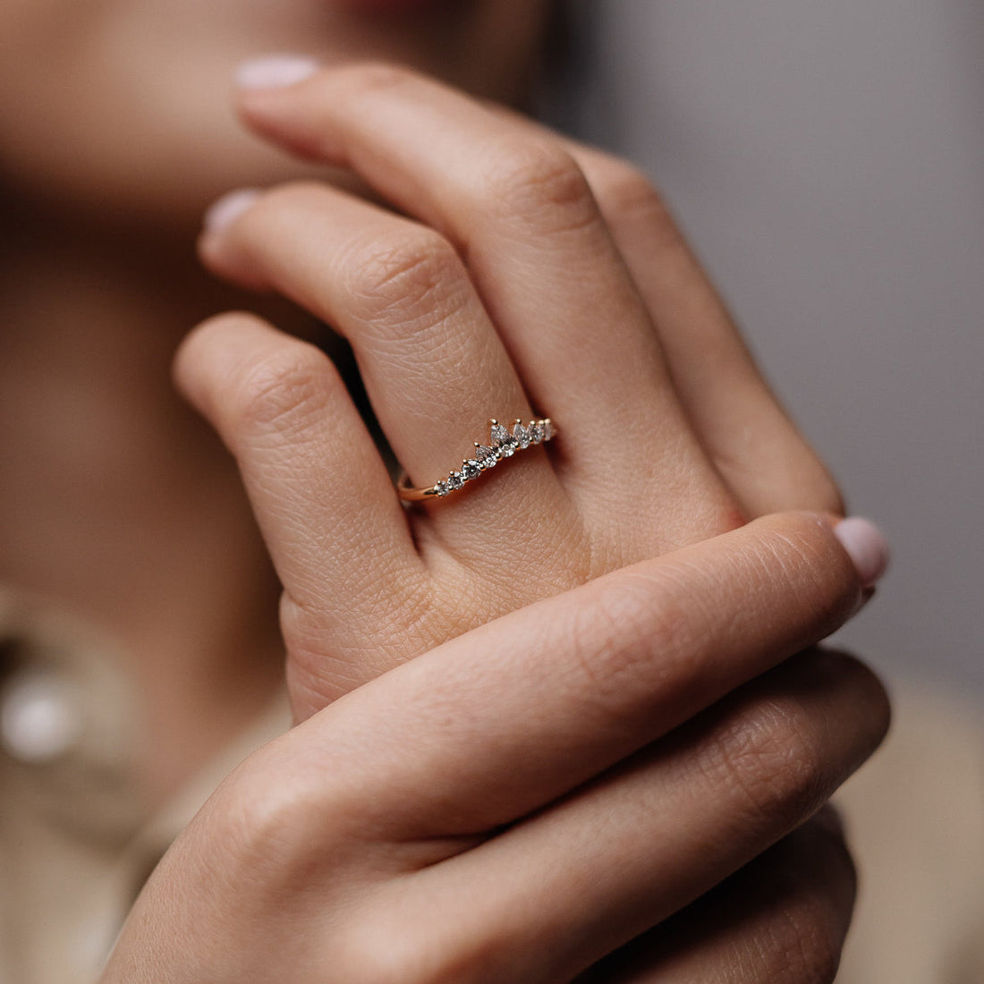 Pear and round lab grown diamond curved wedding band in yellow gold worn on a finger