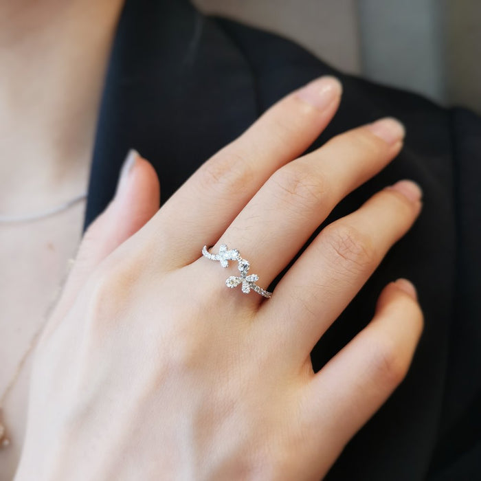 Moissanite butterfly cluster band in white gold worn on a hand resting on a dark jacket