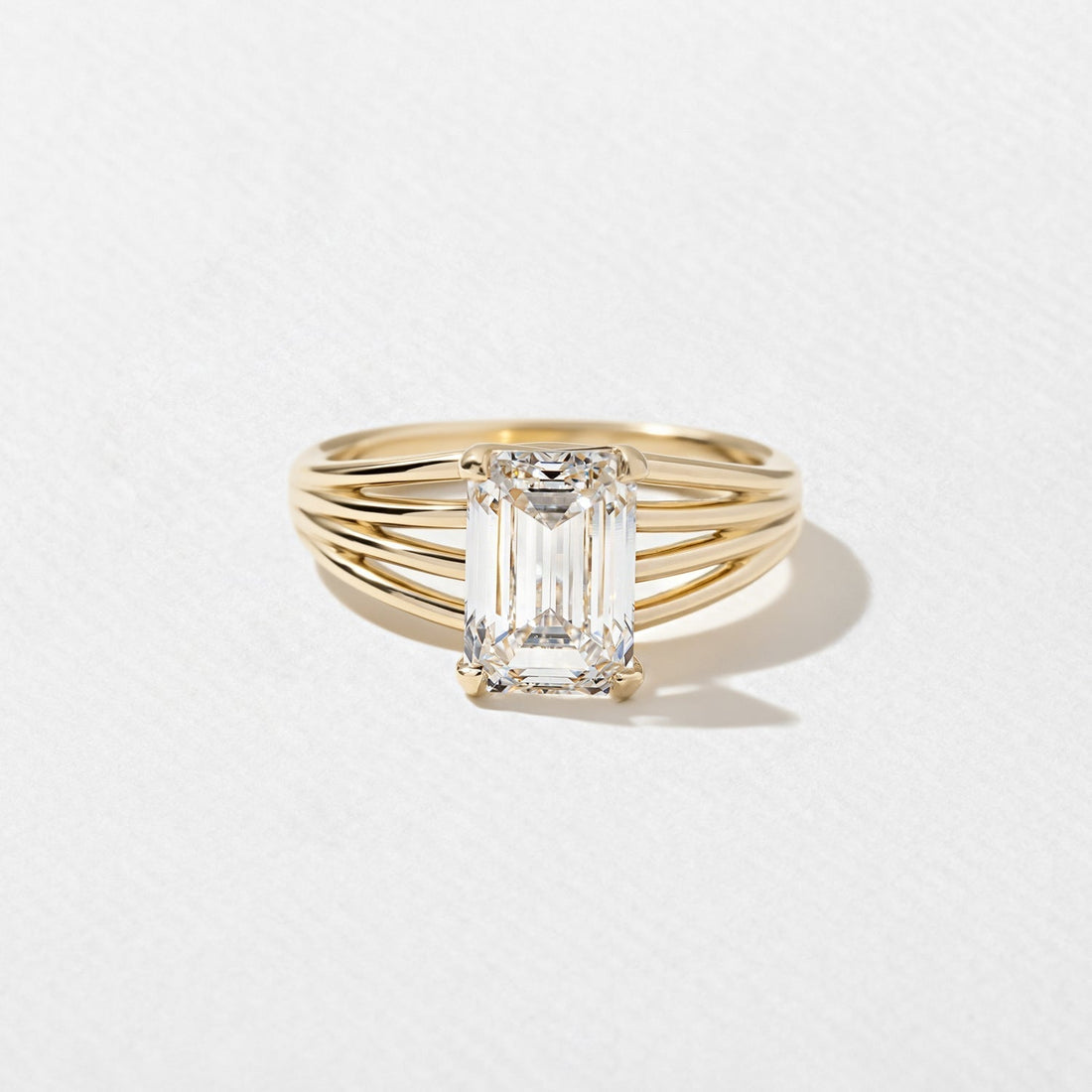 Emerald cut lab grown diamond ring on a ribbed multi rail shank in yellow gold
