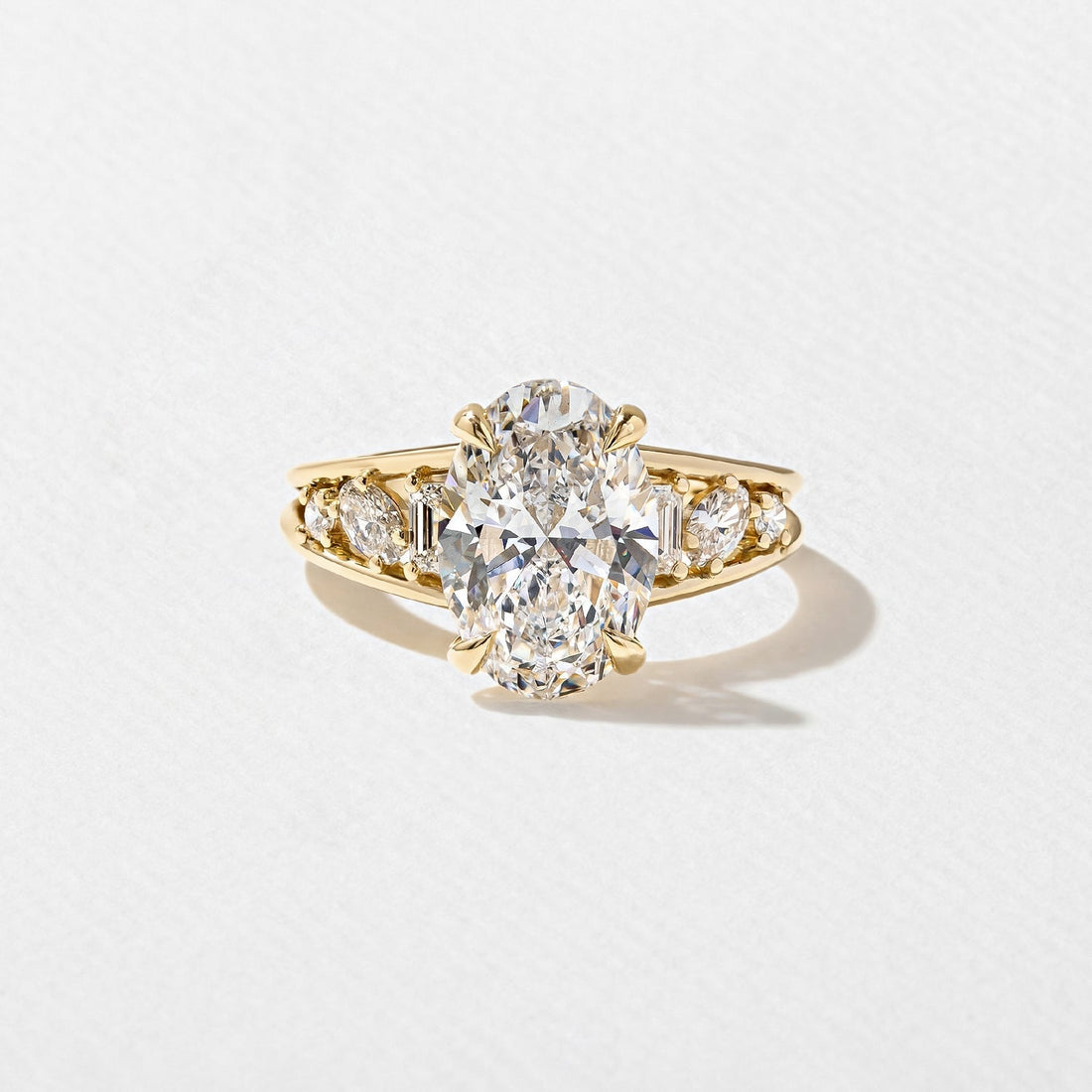 Oval cut lab grown diamond ring with cluster set shoulders in yellow gold