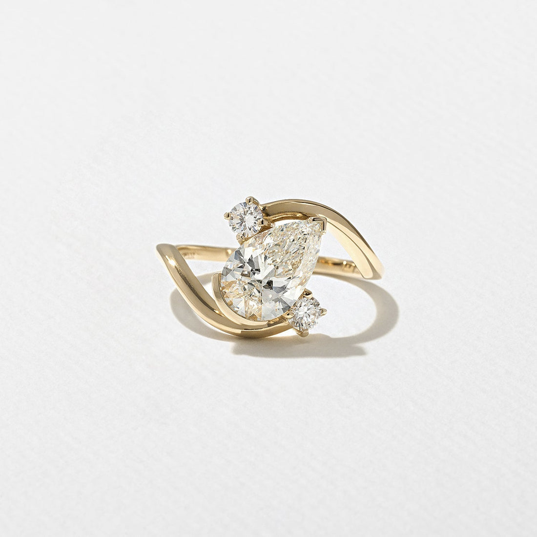 Pear cut lab grown diamond sculptural swirl engagement ring with round accents in yellow gold