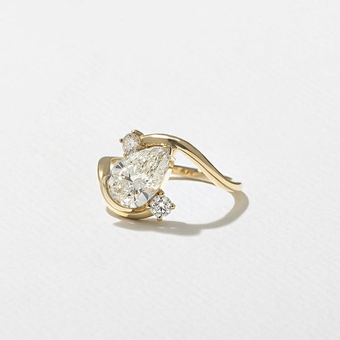Pear cut lab grown diamond sculptural swirl engagement ring with round accents in yellow gold