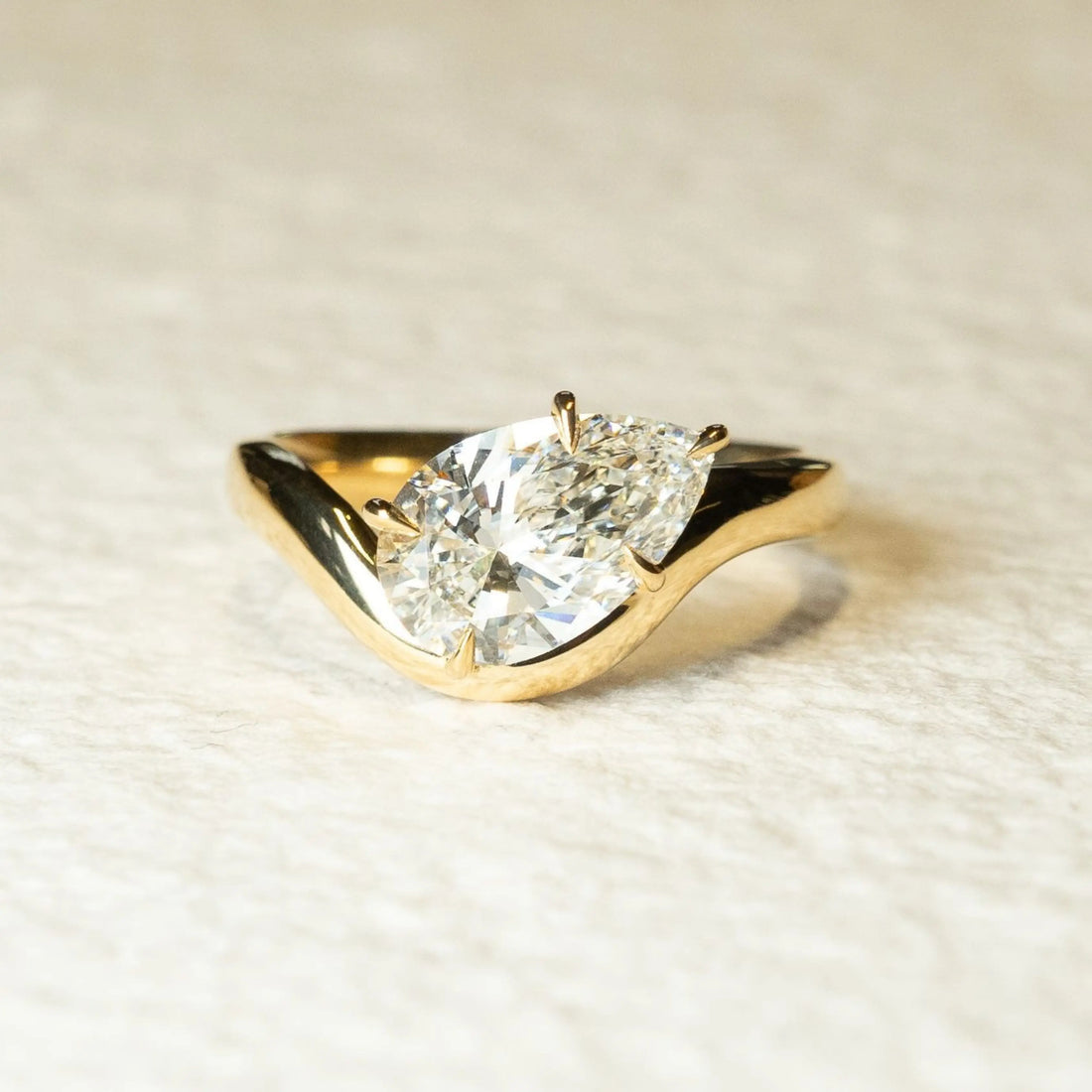 East west pear moissanite solitaire engagement ring with curved band in 14K gold