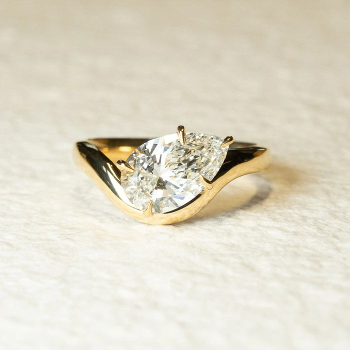 East west pear moissanite solitaire engagement ring with curved band in 14K gold