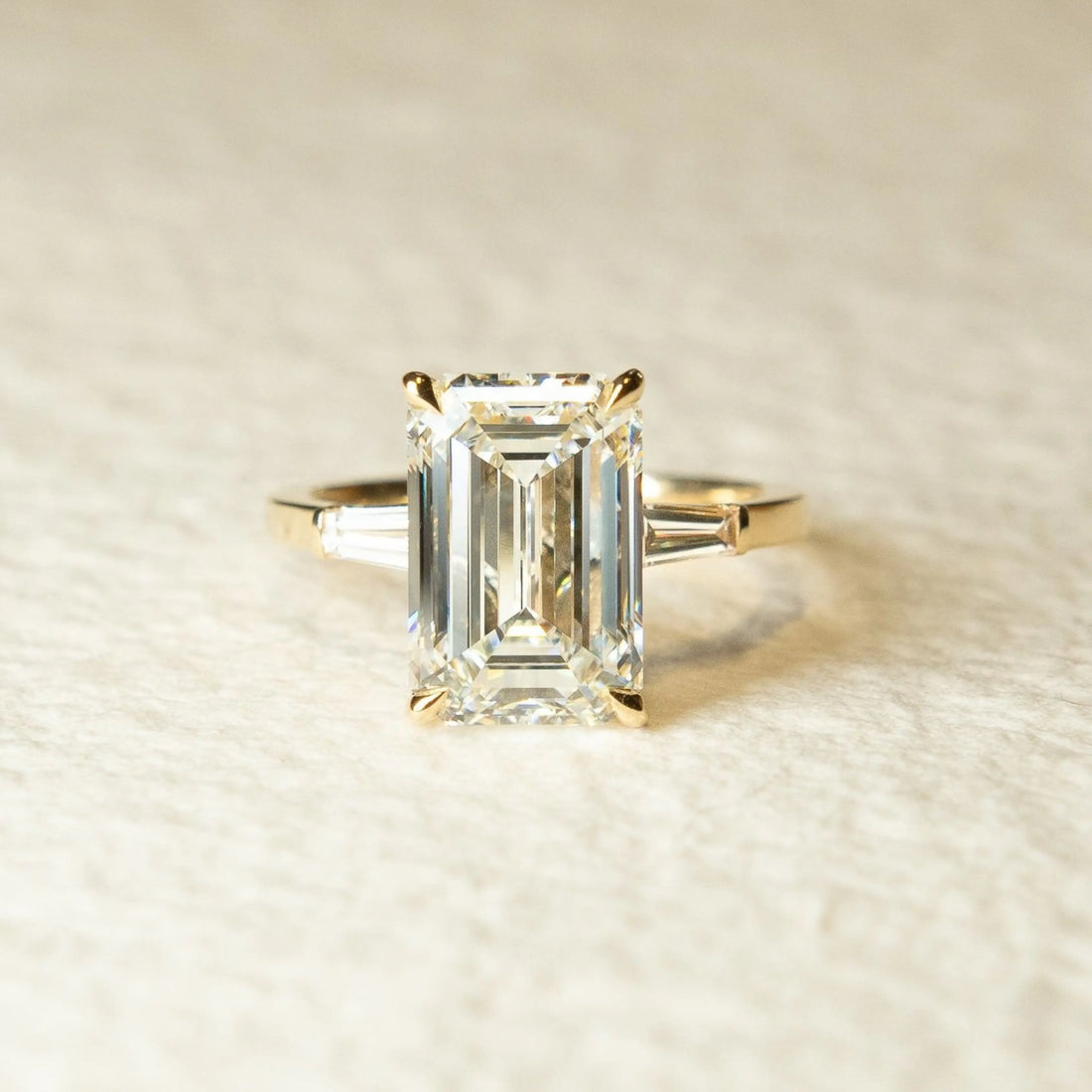 Emerald cut moissanite three stone engagement ring with tapered baguette sides in 14K gold