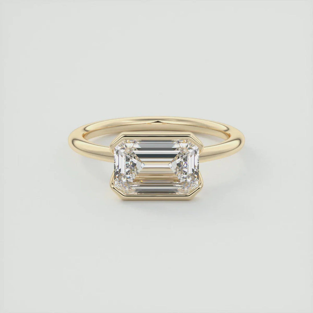 Emerald cut moissanite east west half bezel solitaire ring in 14K gold