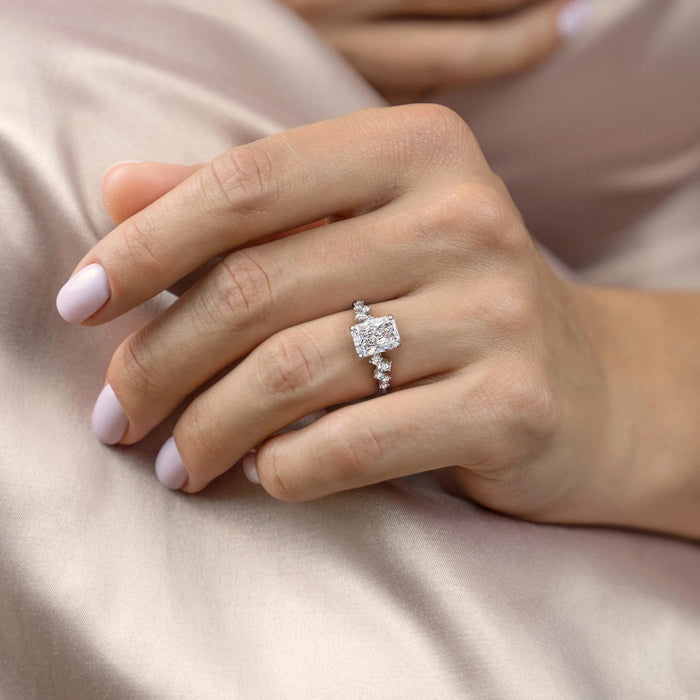 Radiant cut moissanite engagement ring with a hidden halo and a band set with small round stones in a scattered cluster pattern, view 2