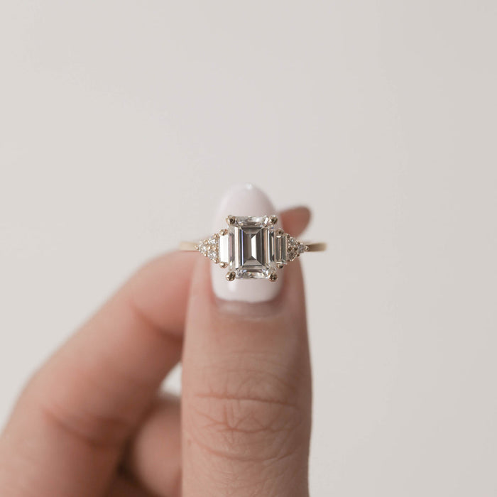 Emerald cut moissanite cluster engagement ring held in hand, front view
