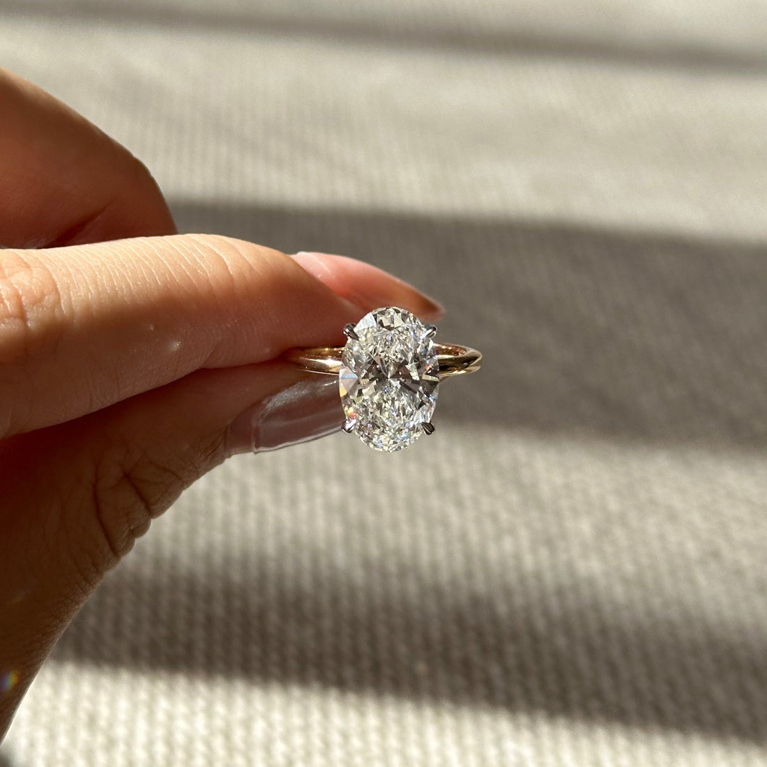 Oval cut lab grown diamond hidden halo solitaire ring on a fine yellow gold band