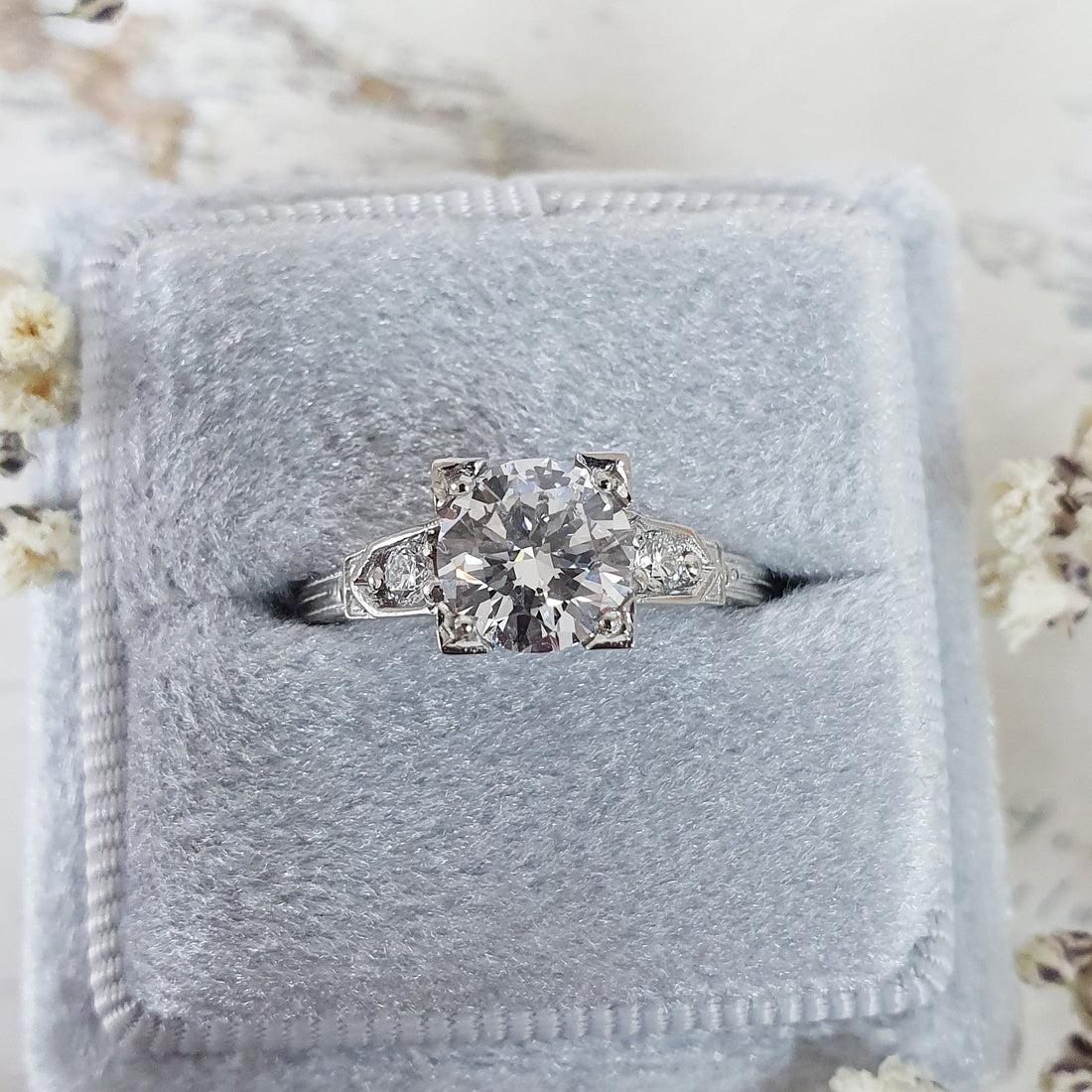 Art deco round cut lab grown diamond ring with a squared head and pave shoulders