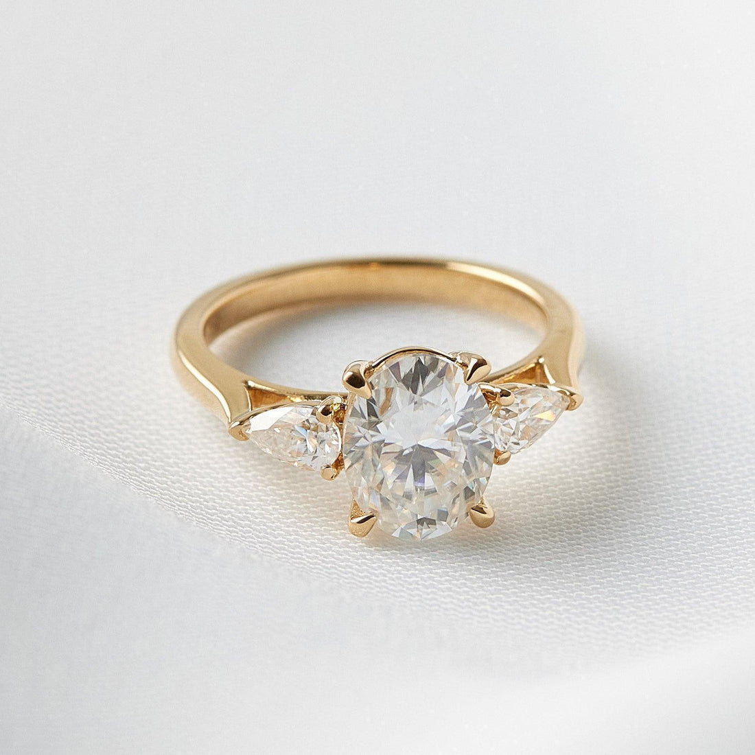 Oval cut lab grown diamond three stone ring with pear sides in yellow gold