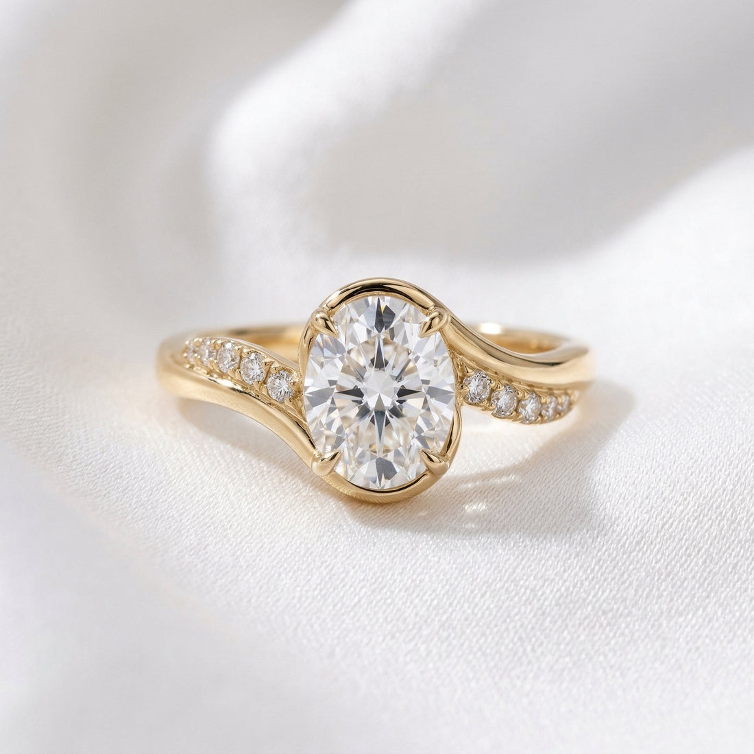 Oval cut lab grown diamond half bezel ring on a crossover pave band in yellow gold