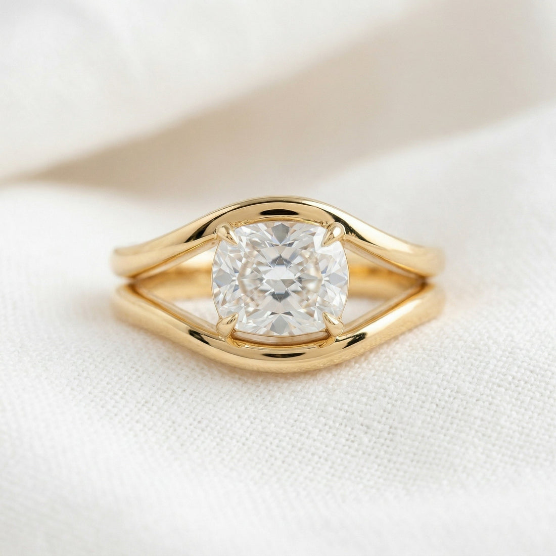 Cushion cut lab grown diamond ring held between heavy split shank arms in yellow gold