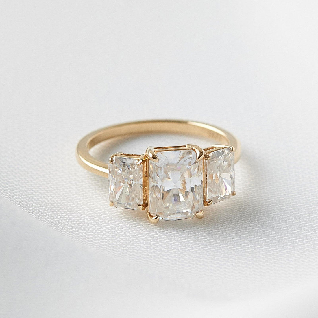 Radiant cut lab grown diamond three stone ring on white fabric