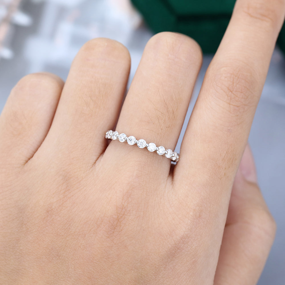 Round moissanite bubble prong wedding band in white gold worn on the finger