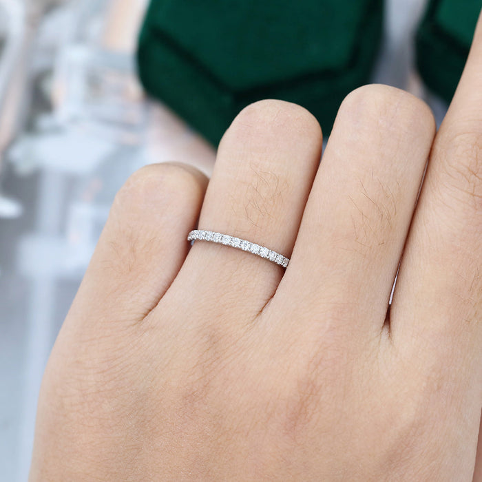 Round moissanite French pave half eternity wedding band in white gold worn on the finger