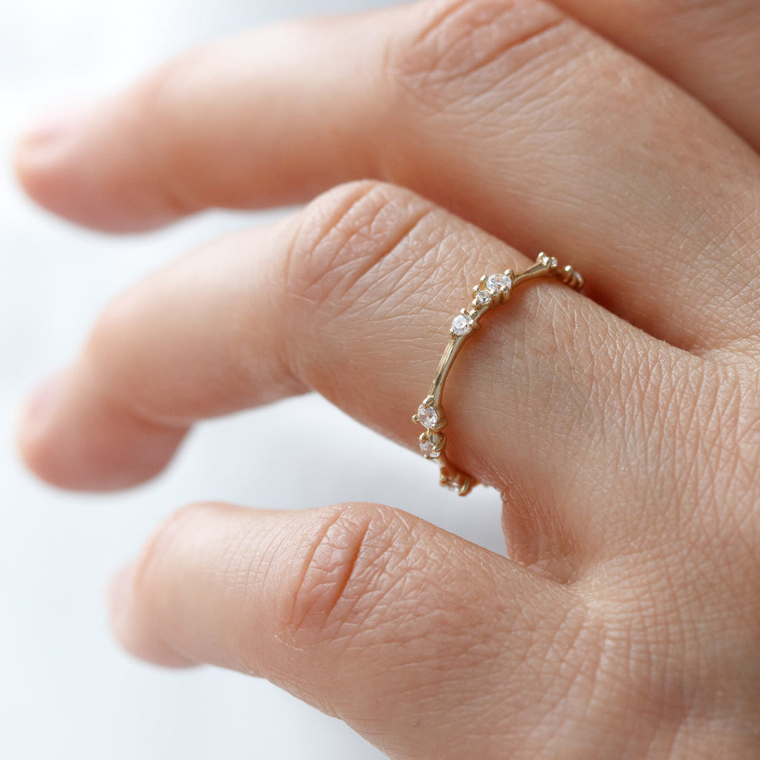 Yellow gold twig style moissanite eternity band worn on a finger
