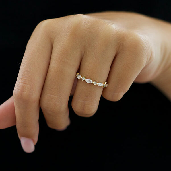 Marquise and round lab grown diamond full eternity wedding band in yellow gold worn on a hand against a dark background
