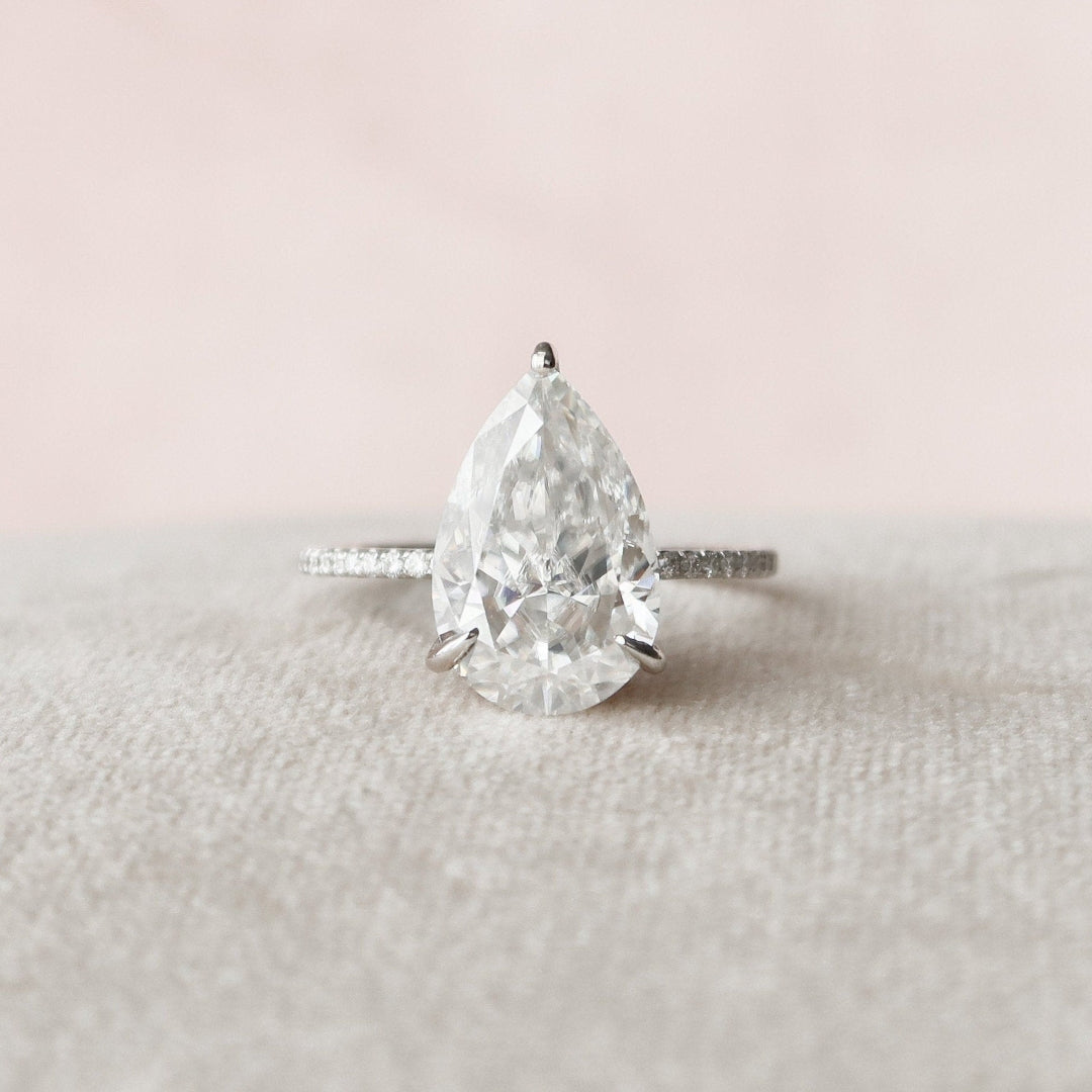 Pear cut moissanite hidden halo engagement ring with eternity band in gold