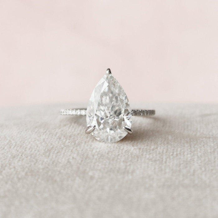 Pear cut moissanite hidden halo engagement ring with eternity band in gold